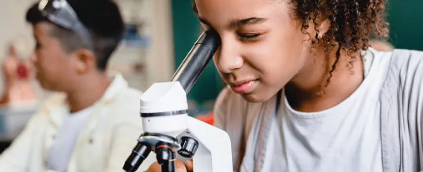 young girl looking into a microscope