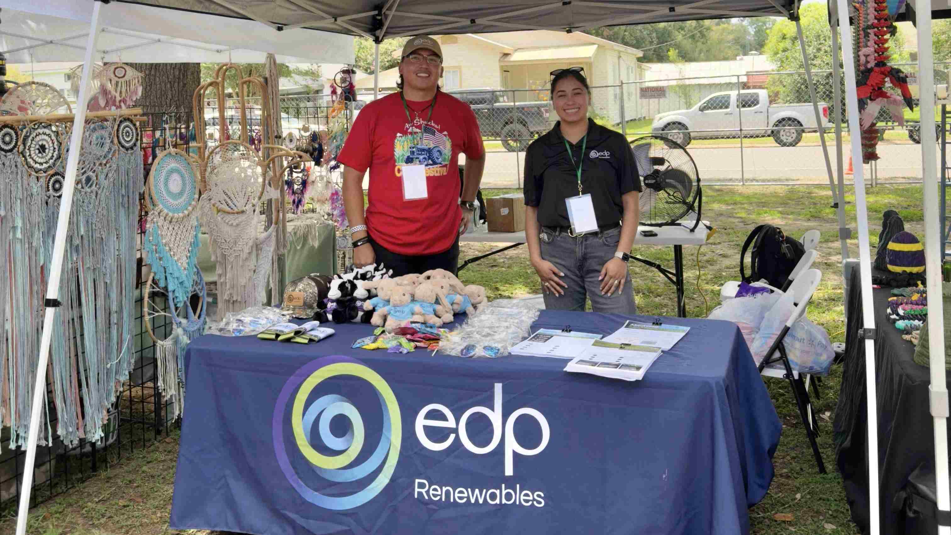 Two people standing behind an EDP Renewables booth table at a community event.