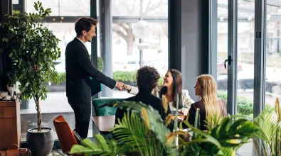 Employee shaking hands with a colleague who is meeting with other employees