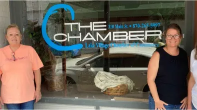 four people standing in front of a window that says the chamber