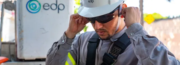 Trabalhador da EDP com capacete e óculos de proteção ajustando o equipamento de segurança