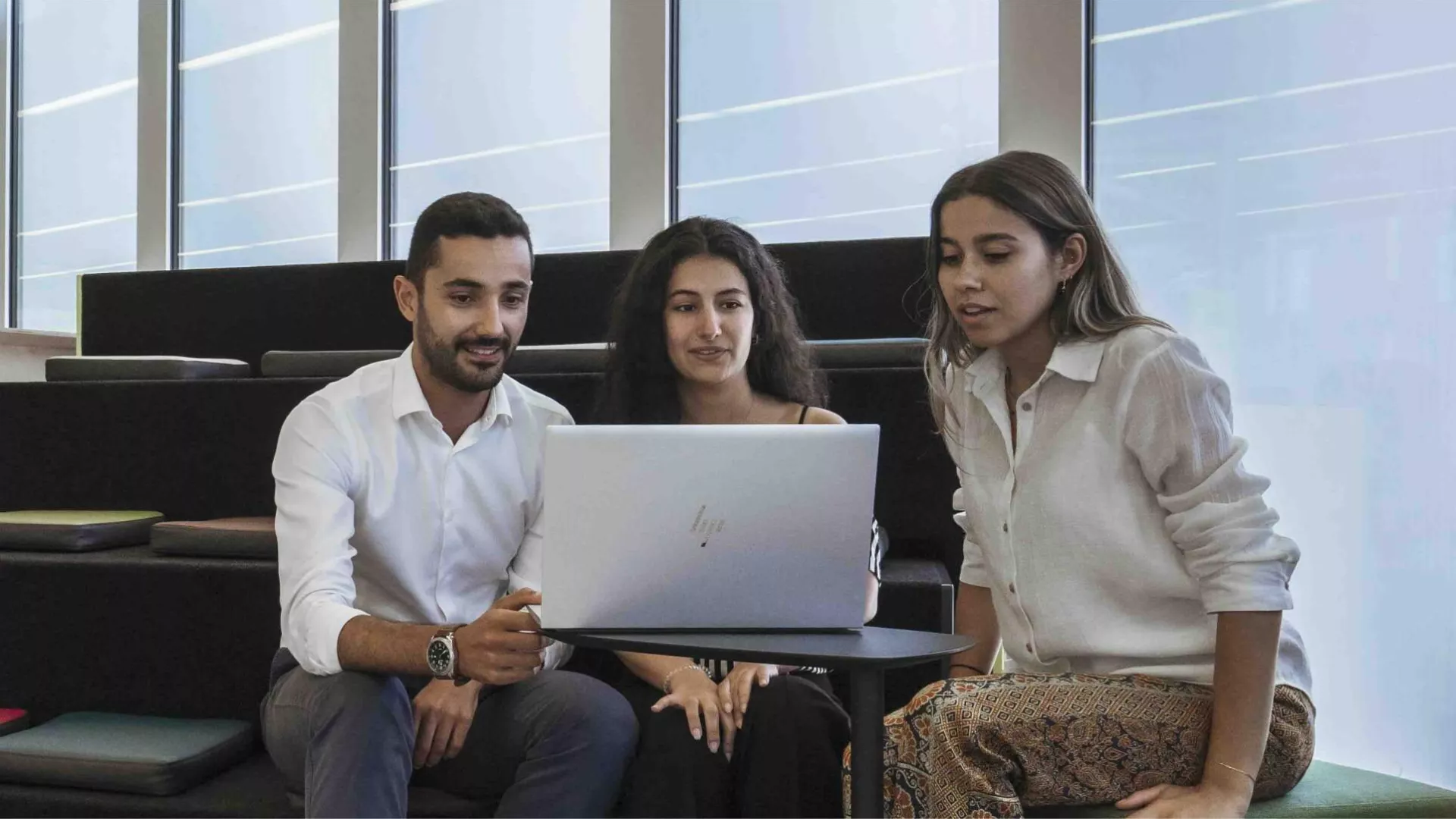 three employees meeting around a computer