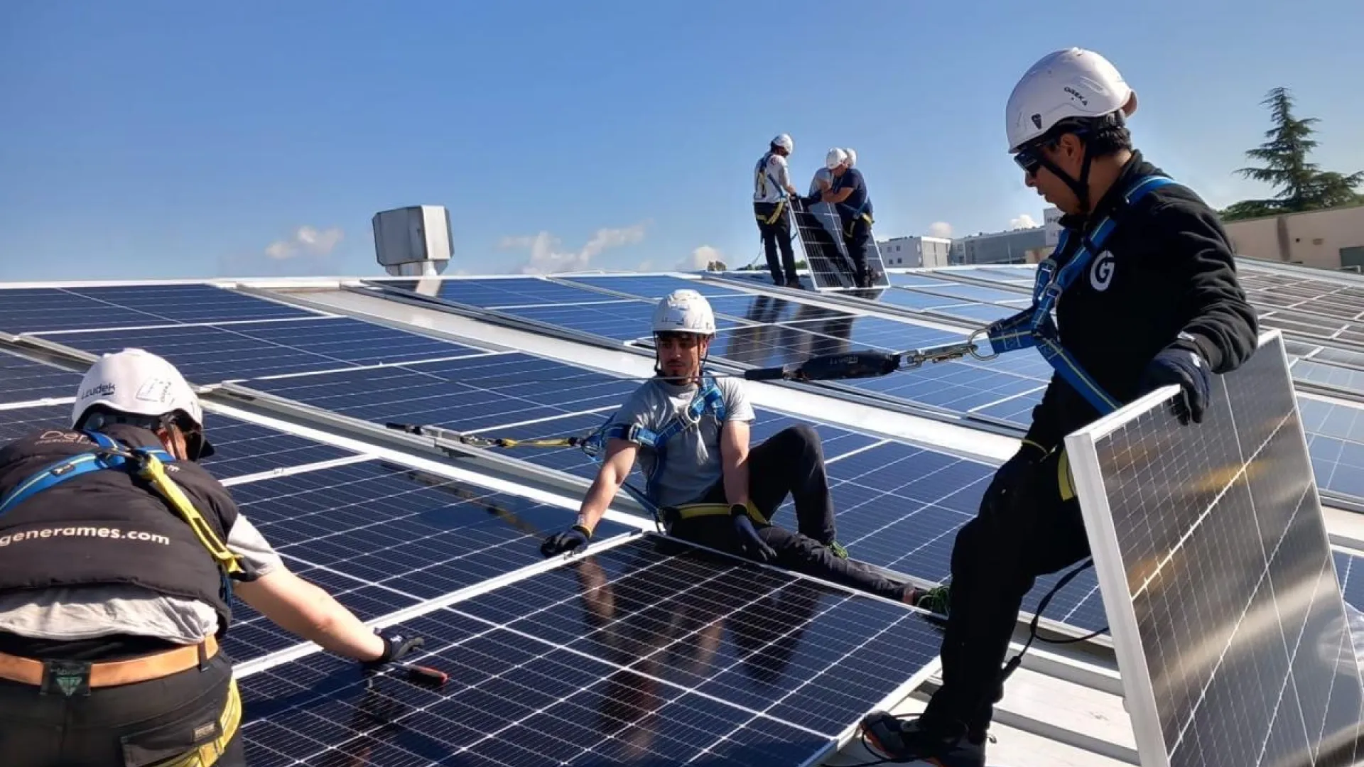 Men installing solar panels on top of a roof