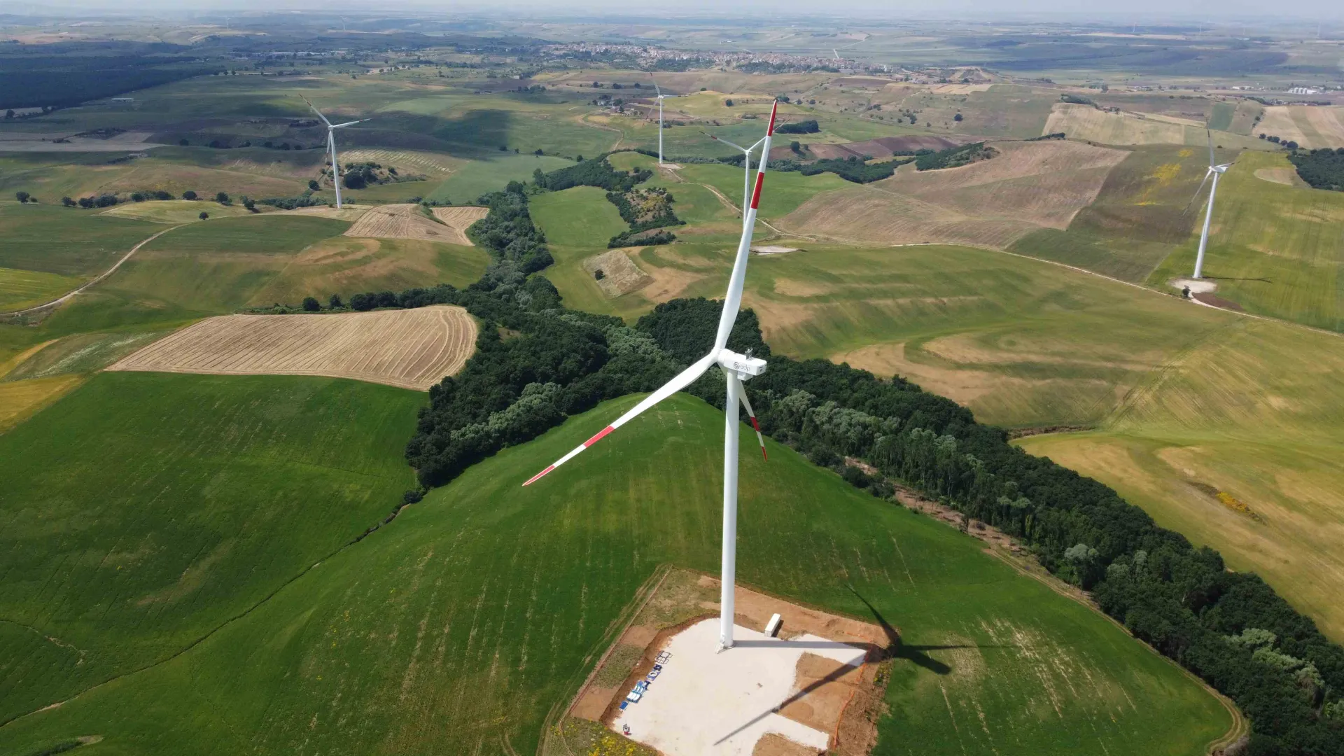 Aerial view of wind turbines scattered across green and brown farmland