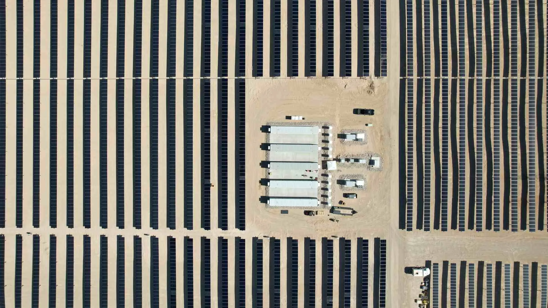 Aerial view of a solar with rows of panels and a central storage system