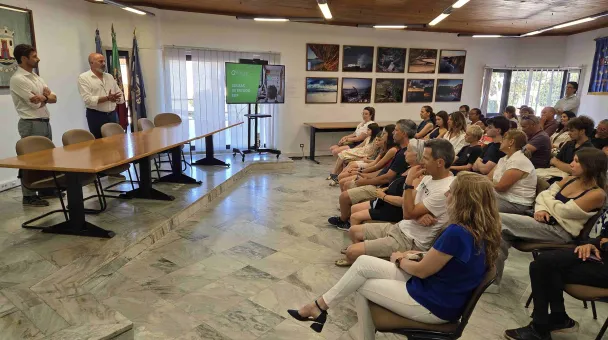 Pessoas reunidas em uma sala assistindo a uma apresentação