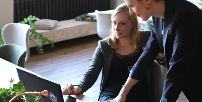 two people looking at a laptop screen.