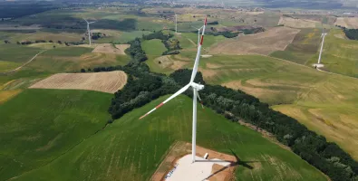 Aerial view of wind turbines scattered across green and brown farmland