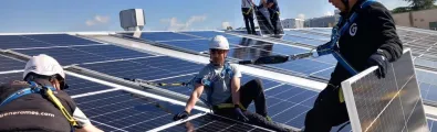 Men installing solar panels on top of a roof
