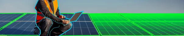 Technician seated with a laptop on a roof covered in solar panels