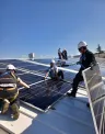 Men installing solar panels on top of a roof