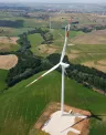 Aerial view of wind turbines scattered across green and brown farmland