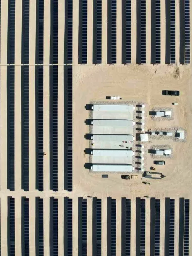 Aerial view of a solar with rows of panels and a central storage system